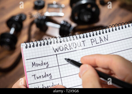 Nahaufnahme eines menschlichen Hand schreiben Workout Plan auf Tagebuch In der Turnhalle Stockfoto