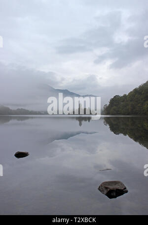 Loch Achray im Herbst Morgen mit Blick auf den Ben Venue eingehüllt in Nebel, Trossachs National Park, Schottland Stockfoto