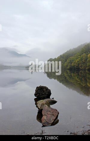 Loch Achray im Herbst Morgen mit Blick auf den Ben Venue eingehüllt in Nebel, Trossachs National Park, Schottland Stockfoto