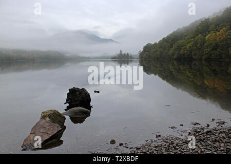 Loch Achray im Herbst Morgen mit Blick auf den Ben Venue eingehüllt in Nebel, Trossachs National Park, Schottland Stockfoto