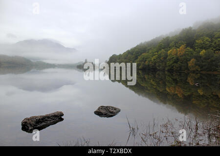 Loch Achray im Herbst Morgen mit Blick auf den Ben Venue eingehüllt in Nebel, Trossachs National Park, Schottland Stockfoto