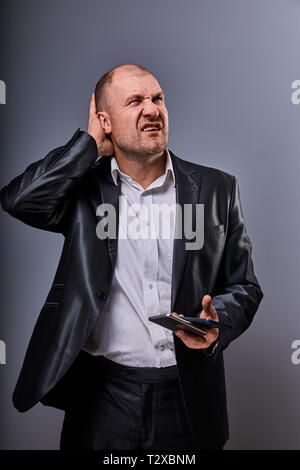 Unglücklich betont wütend Geschäftsmann Gespräch am Handy sehr emotional in Bürosoftware auf grauem Hintergrund. Closeup Portrait Stockfoto