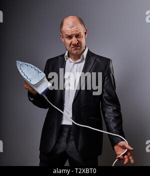 Kahlen Spaß düsterer aggressiver Comic business Mann, der das Haus Eisen und wollen in der Klage auf grauem Hintergrund zu schlagen. Closeup Portrait Stockfoto