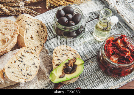 Hausgemachtes Brot mit Oliven und getrockneten Tomaten, Avocado und Olivenöl. Stockfoto