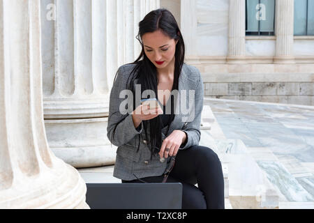 Elegante Frau gerade ihre mobile beim Arbeiten mit Ihrem Laptop Stockfoto