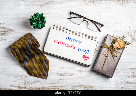 Der glückliche Vater tag Konzept. Flach Bild der Geschenkbox, Krawatte, Gläser und Notebook mit Der glückliche Vater Tag Text. Stockfoto