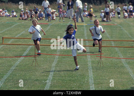 Grundschule Kinder in Hurdle Race beim Sport Tag konkurrierenden Stockfoto