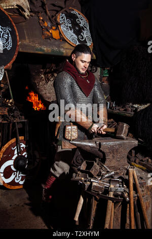 Viking Schmieden Waffen und Schwerter in der Schmiede. Ein Mann in der ...