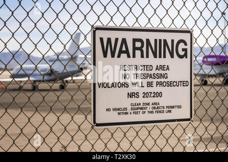 LAS VEGAS, Nevada, USA - Februar 2019: Warnschild an einen Zaun um den internationalen Flughafen McCarran. Im Hintergrund sind private Executive Jets. Stockfoto