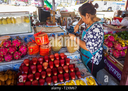 Phuket, Thailand, März 2013, Thai Frau Läuten der Durian Frucht auf dem freien Markt, frischen, tropischen Früchten, in Haufen auf Bänken gestapelt Stockfoto