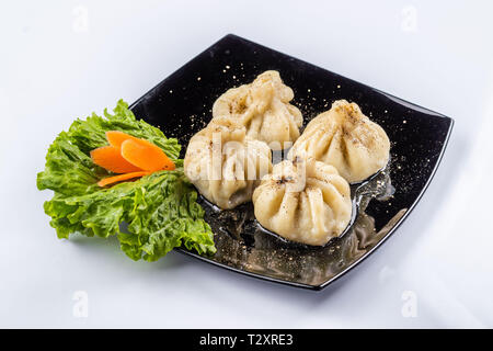Georgische Knödel Khinkali mit Fleisch und roten Papper, auf schwarze Platte Stockfoto