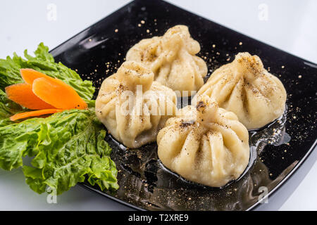 Georgische Knödel Khinkali mit Fleisch und roten Papper, auf schwarze Platte Stockfoto