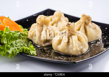 Georgische Knödel Khinkali mit Fleisch und roten Papper, auf schwarze Platte Stockfoto