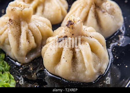 Georgische Knödel Khinkali mit Fleisch und roten Papper, auf schwarze Platte Stockfoto