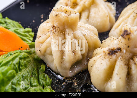Georgische Knödel Khinkali mit Fleisch und roten Papper, auf schwarze Platte Stockfoto