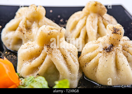 Georgische Knödel Khinkali mit Fleisch und roten Papper, auf schwarze Platte Stockfoto