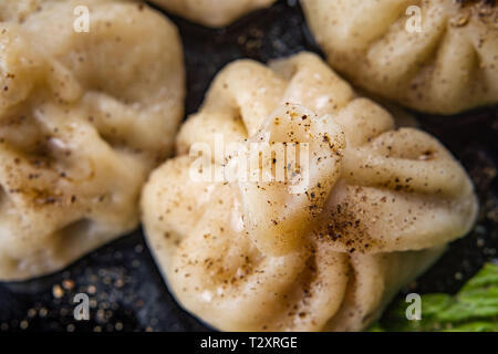 Georgische Knödel Khinkali mit Fleisch und roten Papper, auf schwarze Platte Stockfoto
