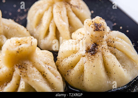 Georgische Knödel Khinkali mit Fleisch und roten Papper, auf schwarze Platte Stockfoto
