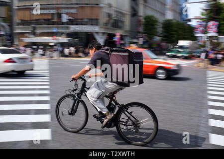 Abgebildet ist ein Radfahrer bei Shibuya Crossing Tokio, Japan. Stockfoto