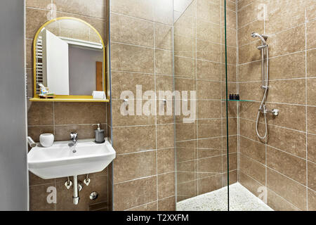 Modernes Interieur Badezimmer mit Waschbecken und Spiegel, Glas begehbare Dusche mit Marmor Fliesen Surround Stockfoto
