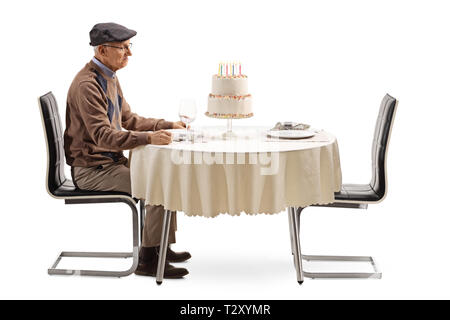 Einsame ältere Mann an einem Tisch sitzen mit einem Geburtstagskuchen auf weißem Hintergrund Stockfoto