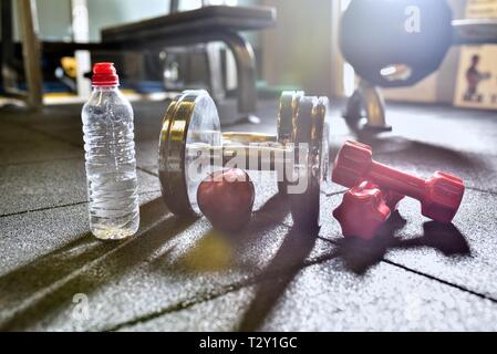 Fitness Concept in Rot, Apple, Hanteln und Wasserflasche auf schwarzem Hintergrund Stockfoto