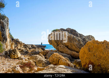 Nicht erkennbare Mann, der auf dem Meer Felsen beim Angeln Stockfoto