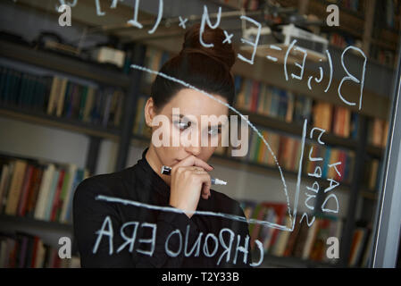 Ausgebildete Business woman Schreiben mathmetical Formel auf Glas Stockfoto
