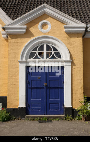 Eine blaue Tür auf einem Gelb lackiert Backsteingebäude auf der Insel Bornholm in Dänemark. Stockfoto