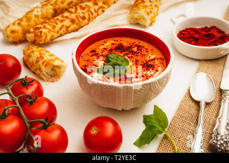 Tomatensuppe mit Basilikum, rote Paprika, Sahne und Knoblauch und Käse Brot Sticks, weißer Hintergrund Stockfoto