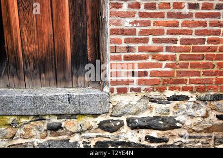 Altes Gebäude, das repariert werden muss, aus Ziegel, Stein und Zement mit Holztür und ist grunge Stockfoto