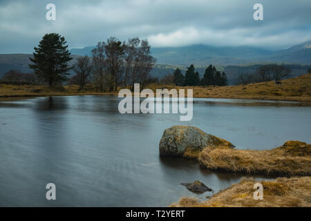 Kelly Halle Tarn ist auf Torver zurück Gemeinsame westlich von Coniston Water. vor der dramatischen Kulisse der alte Mann der Coniston gelegen. Stockfoto
