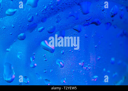 Random Wassertropfen auf der Oberfläche aus Glas mit blauem Licht Hintergrund Stockfoto
