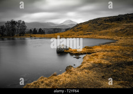 Kelly Halle Tarn ist auf Torver zurück Gemeinsame westlich von Coniston Water. vor der dramatischen Kulisse der alte Mann der Coniston gelegen. Stockfoto