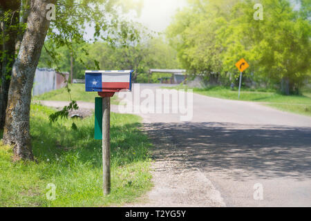 Mailbox mit einem Texas flag entlang einer Landstraße gemalt. Grüne Bäume im Hintergrund. Stockfoto