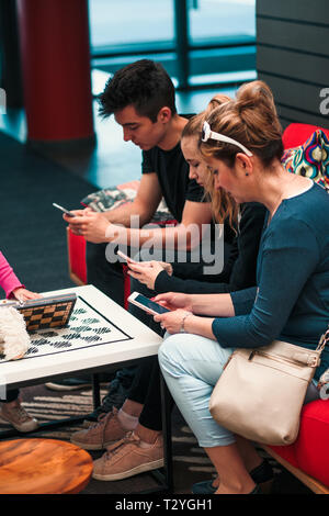 Familie mit Handys zusammen, sitzen auf den Sofas in der Lounge im Hotel Stockfoto