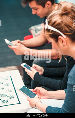 Familie mit Handys zusammen, sitzen auf den Sofas in der Lounge im Hotel Stockfoto