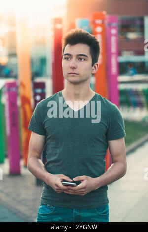 Junger Mann, Smartphone, stehend auf der Straße im Zentrum der Stadt Stockfoto