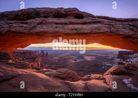 Blick durch arch Mesa Arch bei Sonnenaufgang, Colorado River Canyon mit der La Sal Mountains hinter, Blick auf Grand View Point Trail, Insel im Himmel Stockfoto