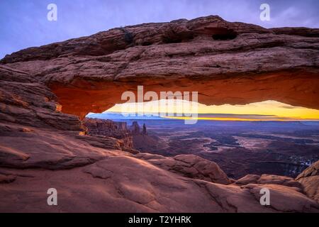 Blick durch arch Mesa Arch bei Sonnenaufgang, Colorado River Canyon mit der La Sal Mountains hinter, Blick auf Grand View Point Trail, Insel im Himmel Stockfoto