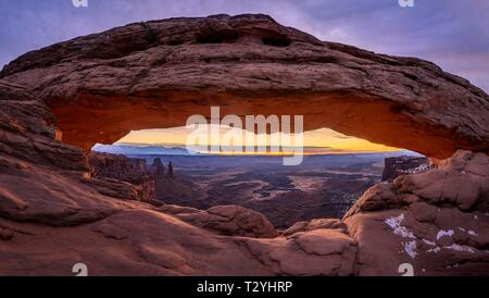 Blick durch arch Mesa Arch bei Sonnenaufgang, Colorado River Canyon mit der La Sal Mountains hinter, Blick auf Grand View Point Trail, Insel im Himmel Stockfoto