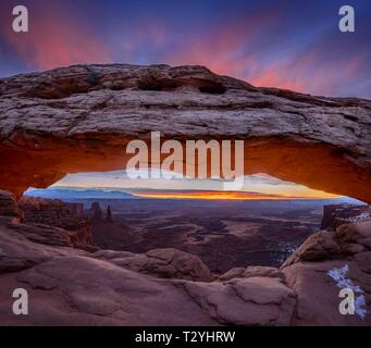 Blick durch arch Mesa Arch bei Sonnenaufgang, Colorado River Canyon mit der La Sal Mountains hinter, Blick auf Grand View Point Trail, Insel im Himmel Stockfoto