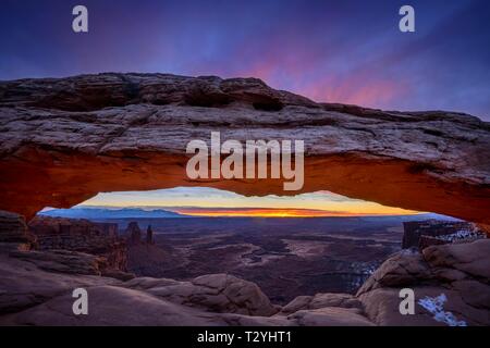 Blick durch arch Mesa Arch bei Sonnenaufgang, Colorado River Canyon mit der La Sal Mountains hinter, Blick auf Grand View Point Trail, Insel im Himmel Stockfoto