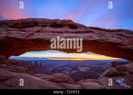 Blick durch arch Mesa Arch bei Sonnenaufgang, Colorado River Canyon mit der La Sal Mountains hinter, Blick auf Grand View Point Trail, Insel im Himmel Stockfoto