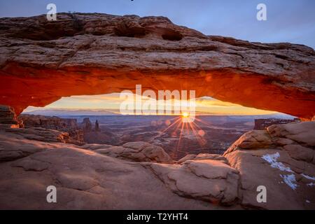 Blick durch arch Mesa Arch bei Sonnenaufgang mit sunstar, Colorado River Canyon mit der La Sal Mountains hinter, Blick auf Grand View Point Trail, Insel Stockfoto