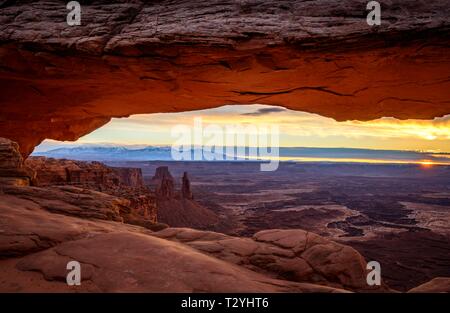 Blick durch arch Mesa Arch bei Sonnenaufgang, Colorado River Canyon mit der La Sal Mountains hinter, Blick auf Grand View Point Trail, Insel im Himmel Stockfoto