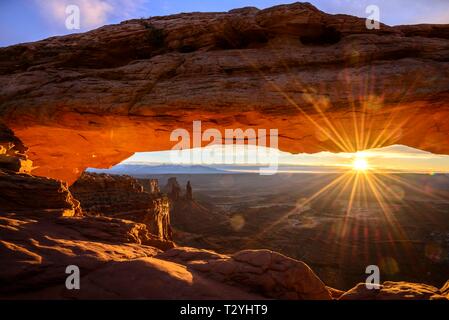 Blick durch arch Mesa Arch bei Sonnenaufgang mit sunstar, Colorado River Canyon mit der La Sal Mountains hinter, Blick auf Grand View Point Trail, Insel Stockfoto