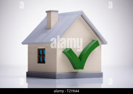 Miniatur Haus Modell mit grünen Häkchen auf weißem Schreibtisch Stockfoto