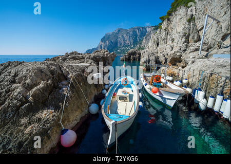 Hell gestrichenen Wassertaxis mit bunten Zubehör angedockt in einer felsigen Bucht im Mittelmeer auf der Insel Capri, Italien Stockfoto