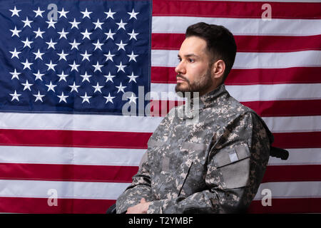 Seitenansicht der Veteran Sitzen im Rollstuhl Vor einer amerikanischen Flagge Stockfoto